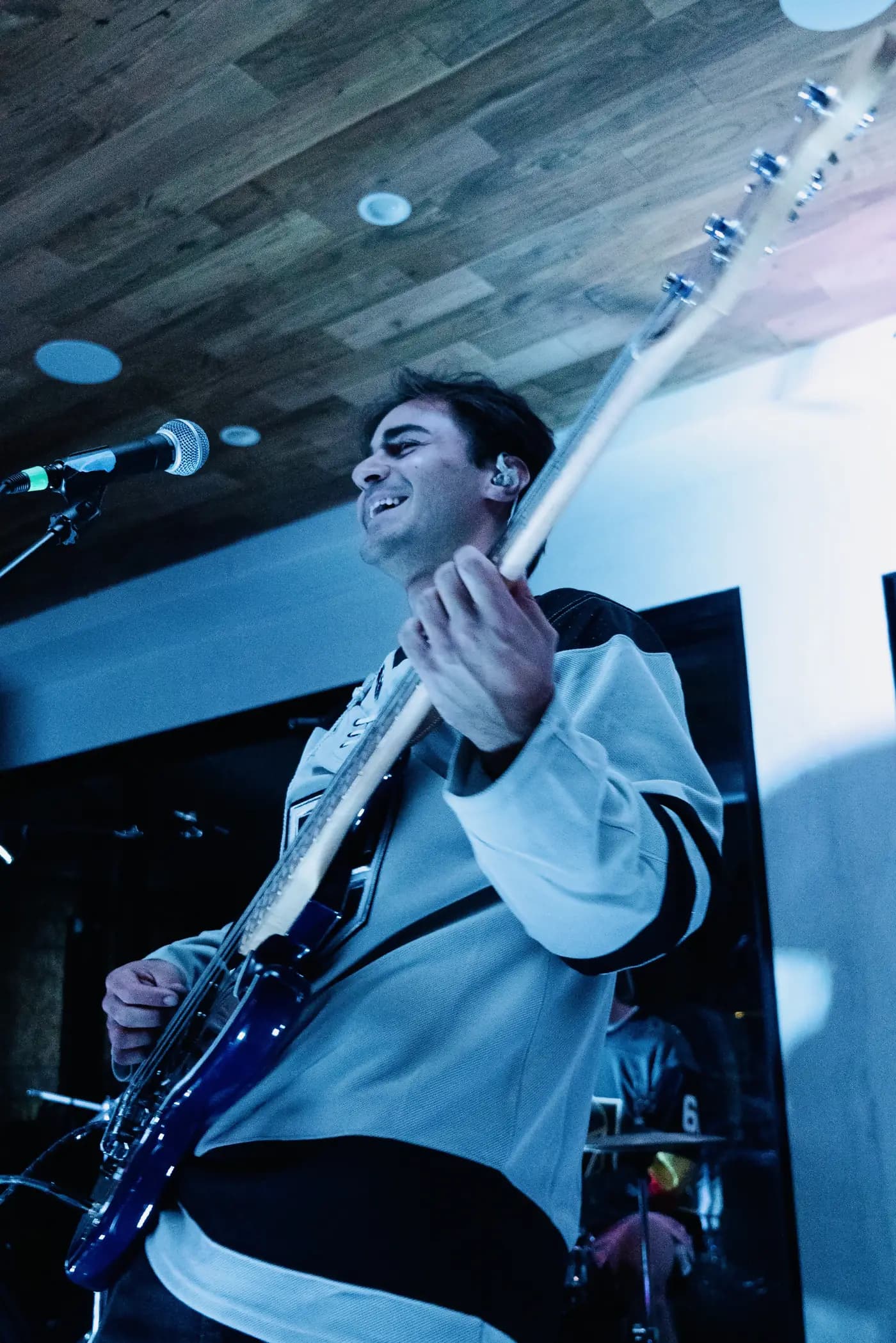Stoke Club's bassist laughing mid-song under a wood ceiling